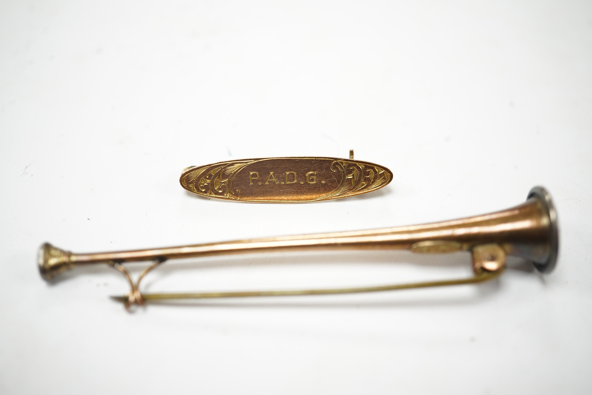 A '9ct and silver' hunting horn bar brooch, 62mm, together with a 1930's yellow metal brooch, with engraved inscription. Condition - fair